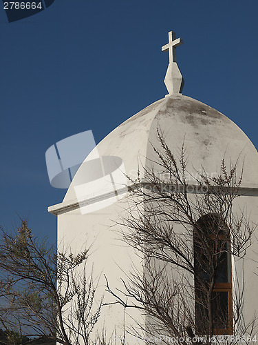 Image of Small white chapel by a tree with blue sky