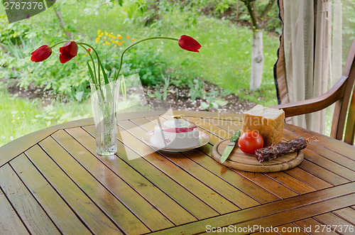 Image of smoked sausage white bread butter and flowers 