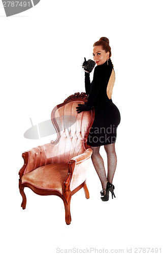 Image of Woman standing on armchair.