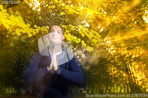 Image of Man in autumn park with namaste greeting
