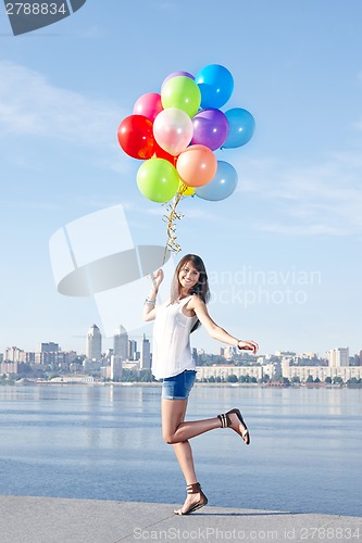 Image of Happy young woman with colorful balloons