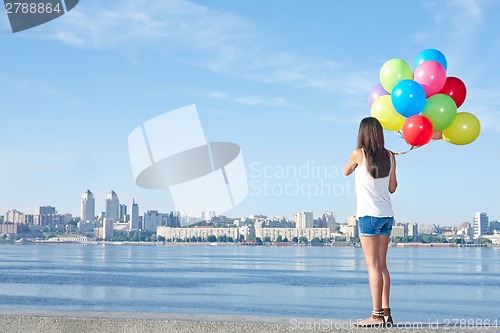 Image of Happy young woman with colorful balloons