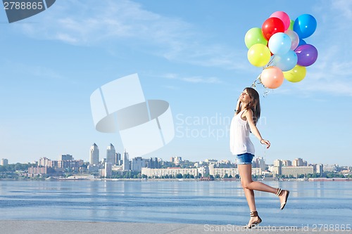 Image of Happy young woman with colorful balloons