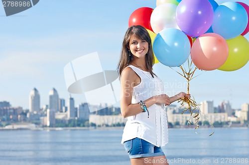 Image of Happy young woman with colorful balloons