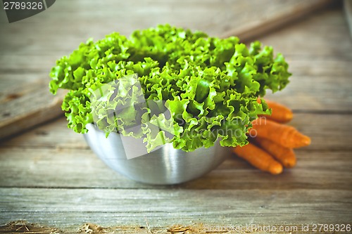 Image of lettuce salad in metal bowl and carrots 