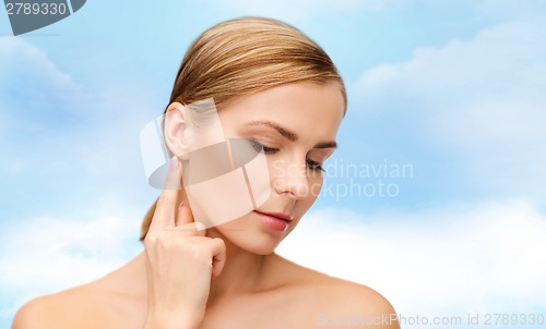 Image of calm woman touching her ear