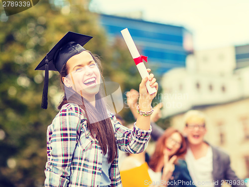 Image of smiling teenage girl in corner-cap with diploma