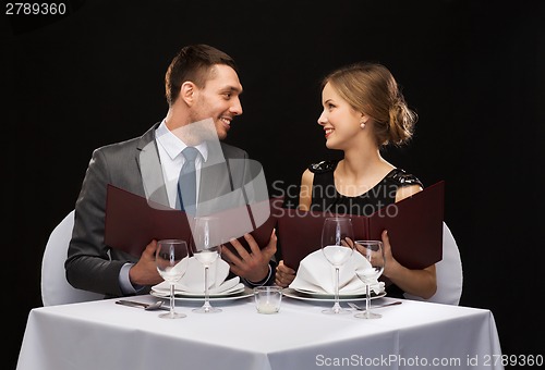 Image of smiling couple with menus at restaurant