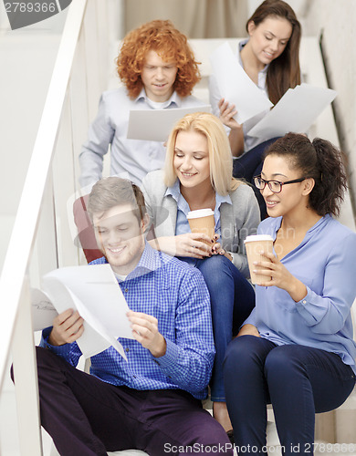 Image of team with papers and take away coffee on staircase