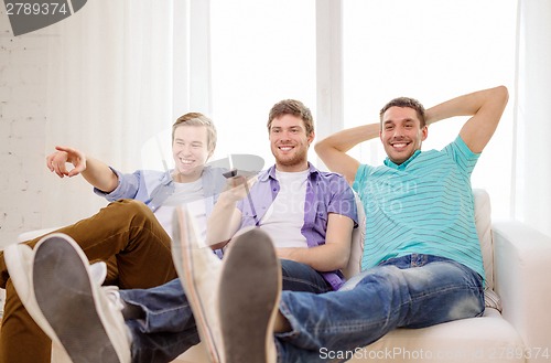 Image of smiling friends with remote control at home