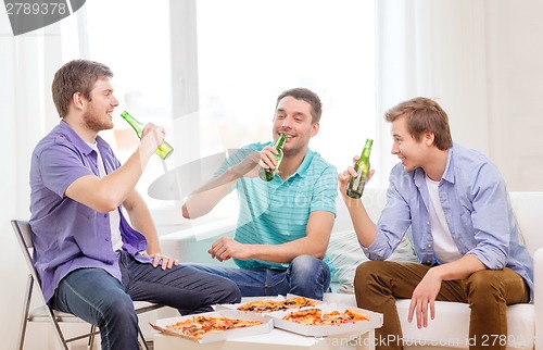 Image of smiling friends with beer and pizza hanging out