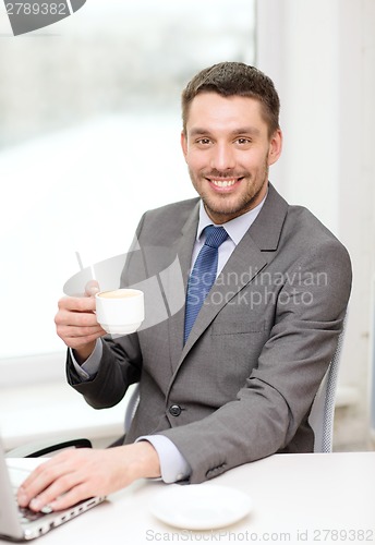 Image of smiling businessman with laptop and coffee