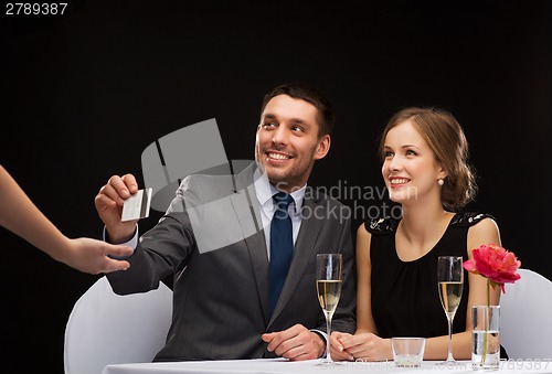 Image of smiling couple paying for dinner with credit card