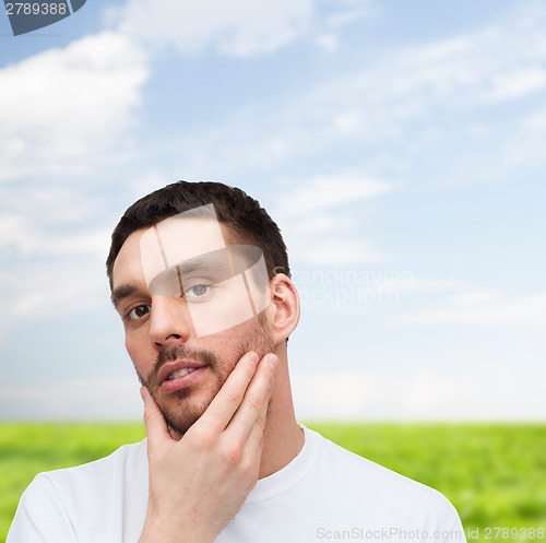 Image of beautiful calm man touching his face