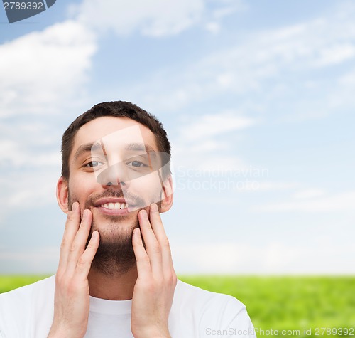 Image of beautiful smiling man touching his face