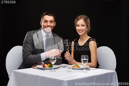 Image of smiling couple eating main course at restaurant