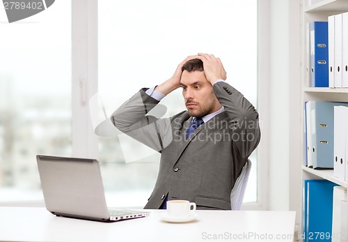 Image of busy businessman with laptop and coffee