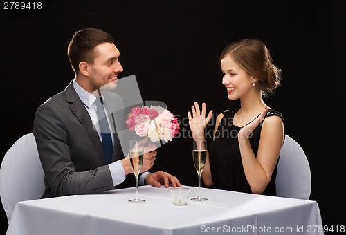 Image of smiling man giving flower bouquet to woman