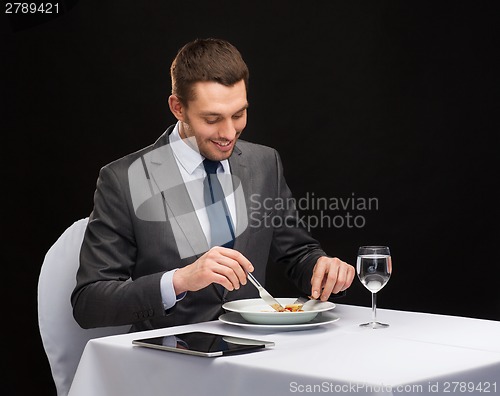 Image of smiling man with tablet pc eating main course