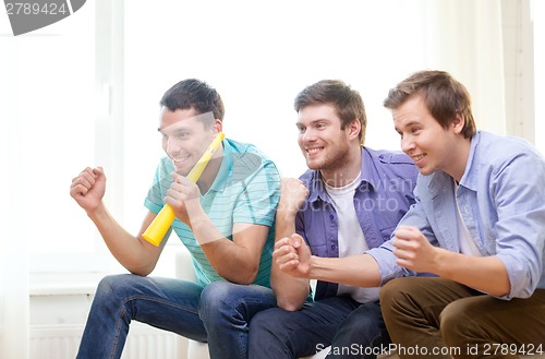 Image of happy male friends with vuvuzela watching sports