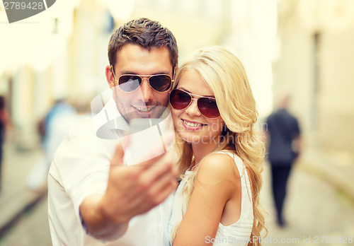 Image of smiling couple with smartphone in the city