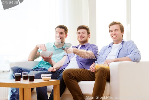 Image of smiling friends with remote control at home