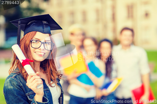 Image of smiling teenage girl in corner-cap with diploma