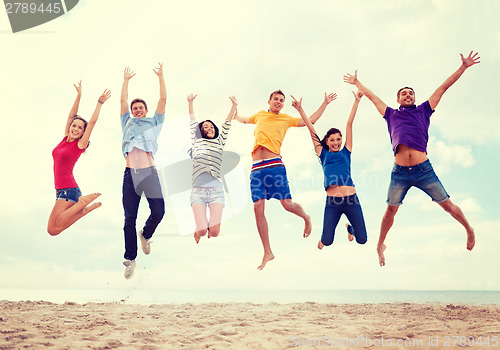 Image of group of friends jumping on the beach