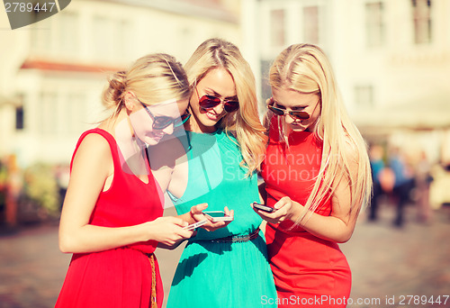 Image of beautiful girls with smartphones in the city