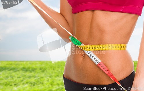 Image of close up of trained belly with measuring tape