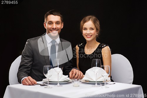 Image of smiling couple holding hands at restaurant