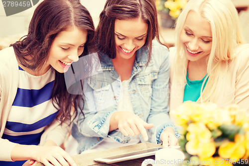 Image of three beautiful girls looking at tablet pc in cafe