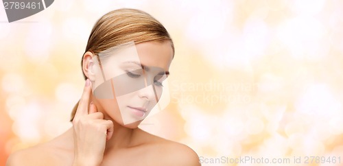 Image of calm woman touching her ear