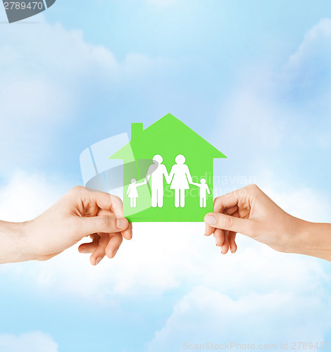 Image of hands holding green house with family