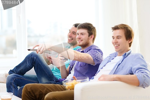 Image of smiling friends with remote control at home