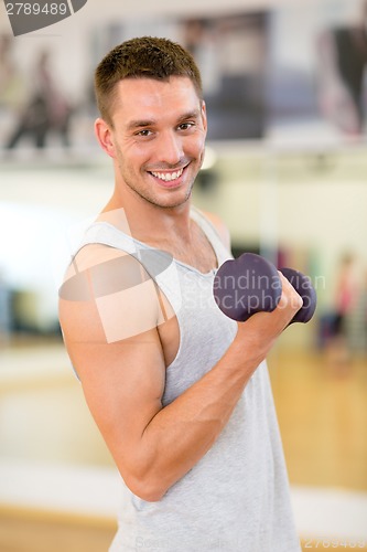 Image of smiling man with dumbbell in gym