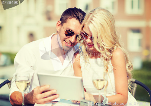 Image of couple looking at tablet pc in cafe