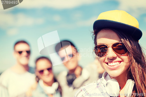 Image of teenage girl with headphones and friends outside