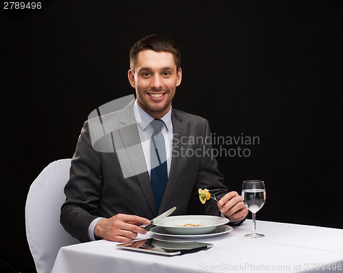 Image of smiling man with tablet pc eating main course