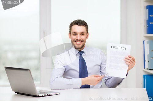 Image of businessman with laptop and contract at office