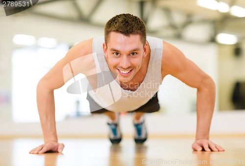 Image of smiling man doing push-ups in the gym