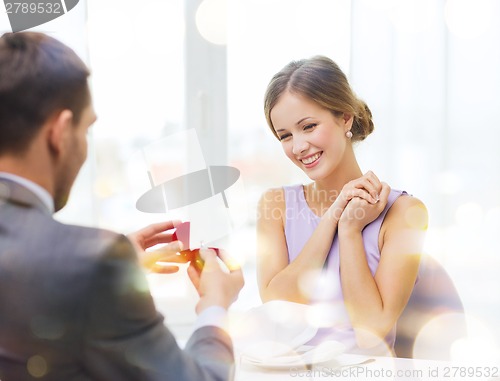 Image of excited young woman looking at boyfriend with ring