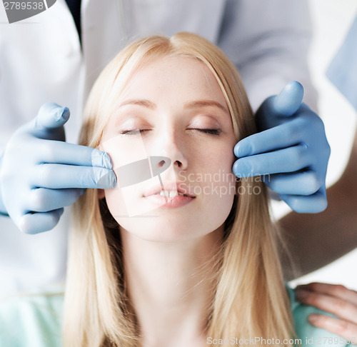 Image of plastic surgeon and nurse with patient