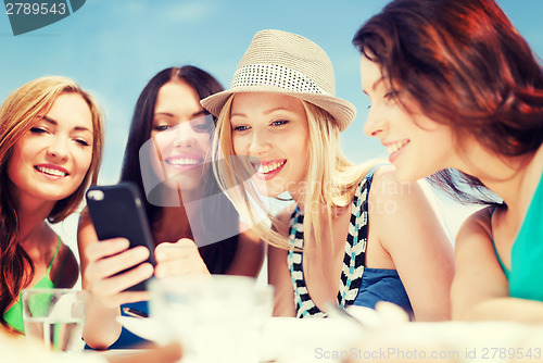 Image of girls looking at smartphone in cafe on the beach