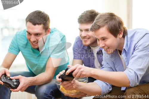 Image of smiling friends playing video games at home