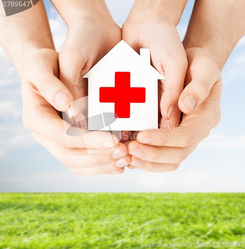 Image of hands holding paper house with red cross