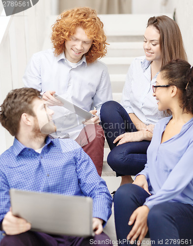 Image of team with laptop and tablet pc on staircase