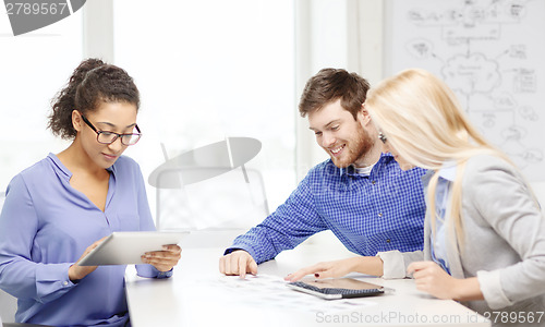 Image of smiling team with table pc and papers working