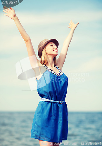 Image of girl with hands up on the beach