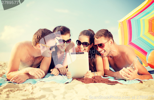 Image of group of smiling people with tablet pc on beach